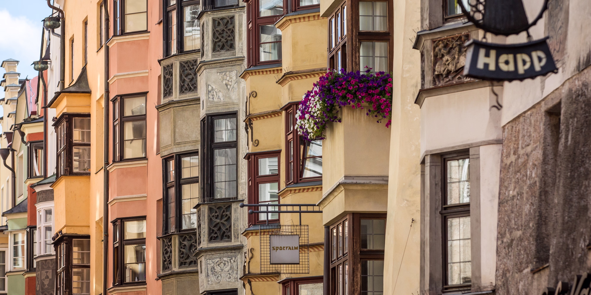 Farbenfrohe historische Häuserfassaden mit kunstvollen Erkern und Blumenschmuck in der Innsbrucker Altstadt.