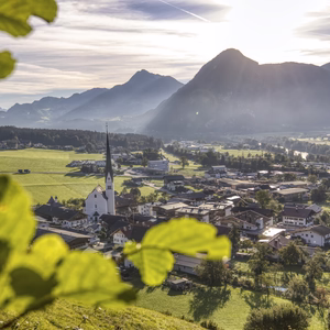 Sonniger Panoramablick auf Wiesing mit Kirche, grünen Wiesen und der markanten Bergkulisse rund um den Achensee.