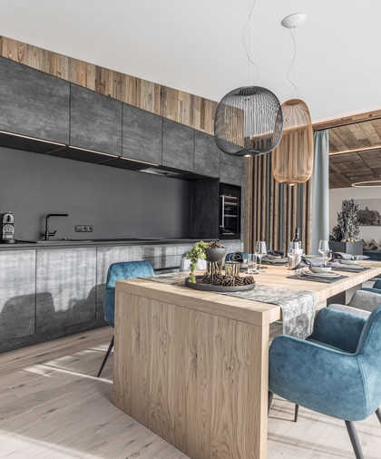 Großzügiger Essbereich im Penthouse mit langem Holztisch, blauen Polsterstühlen und moderner offener Küchenzeile.