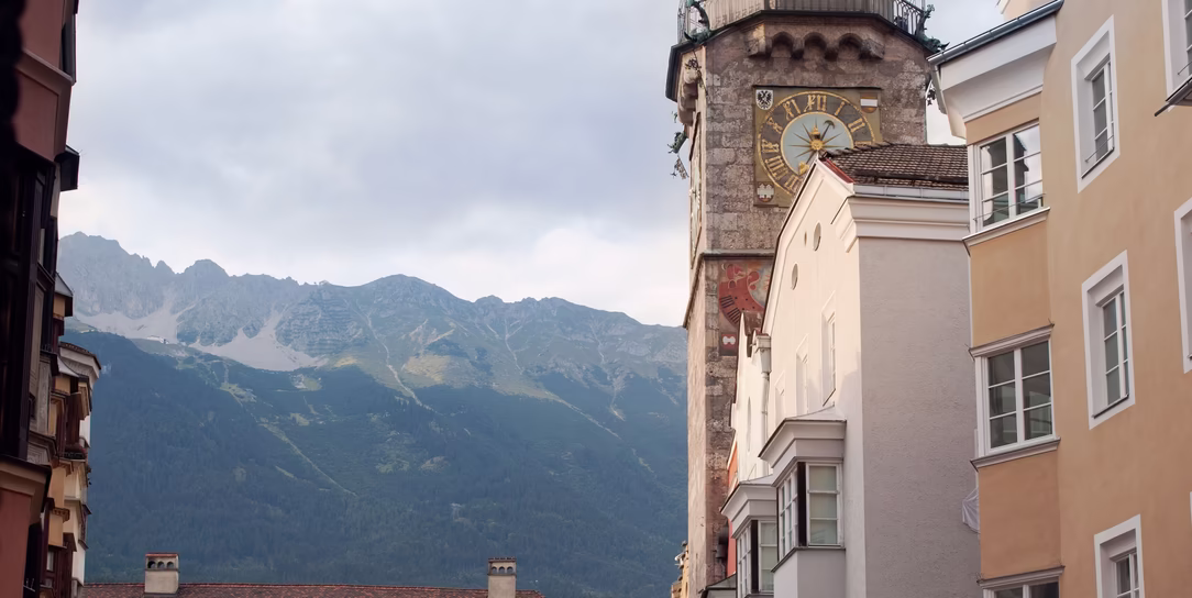 Blick durch die Innsbrucker Altstadt auf den historischen Stadtturm, das Goldene Dachl und die Nordkette im Hintergrund.