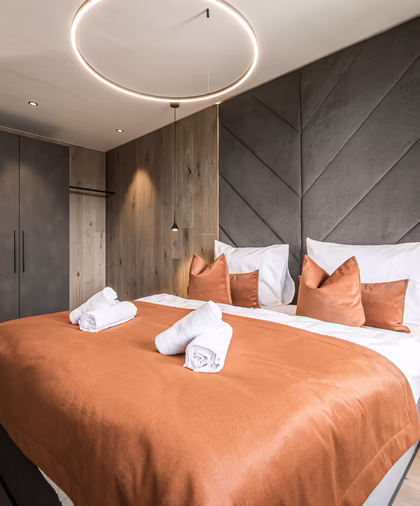 Das stilvolle Schlafzimmer der Panorama Nature Lodge bietet ein großes Doppelbett, warme Holzelemente und eine moderne Beleuchtung.