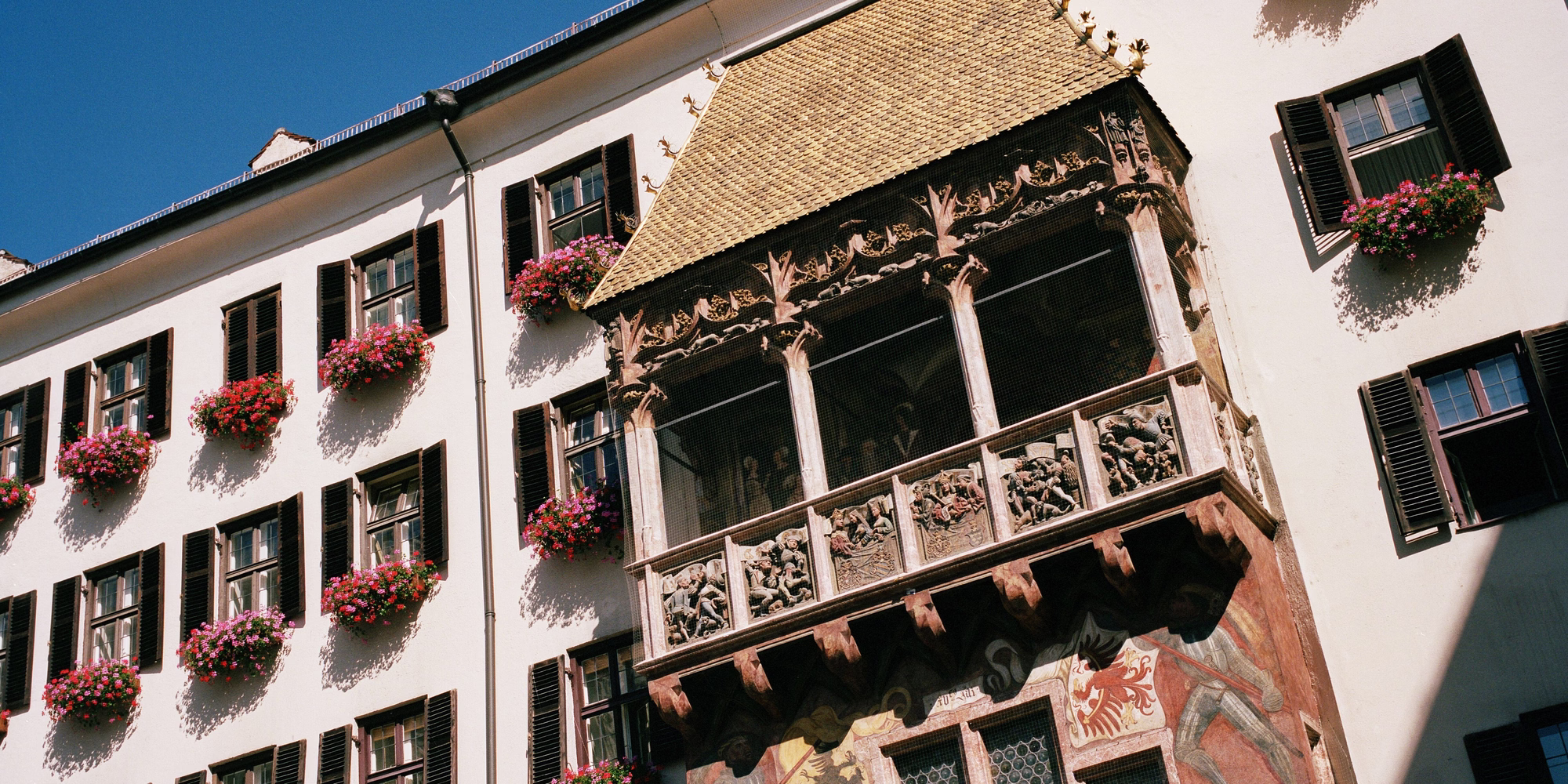 Nahansicht des Goldenen Dachls mit kunstvoll verziertem Erker und blumengeschmückter Fassade in der Innsbrucker Altstadt.